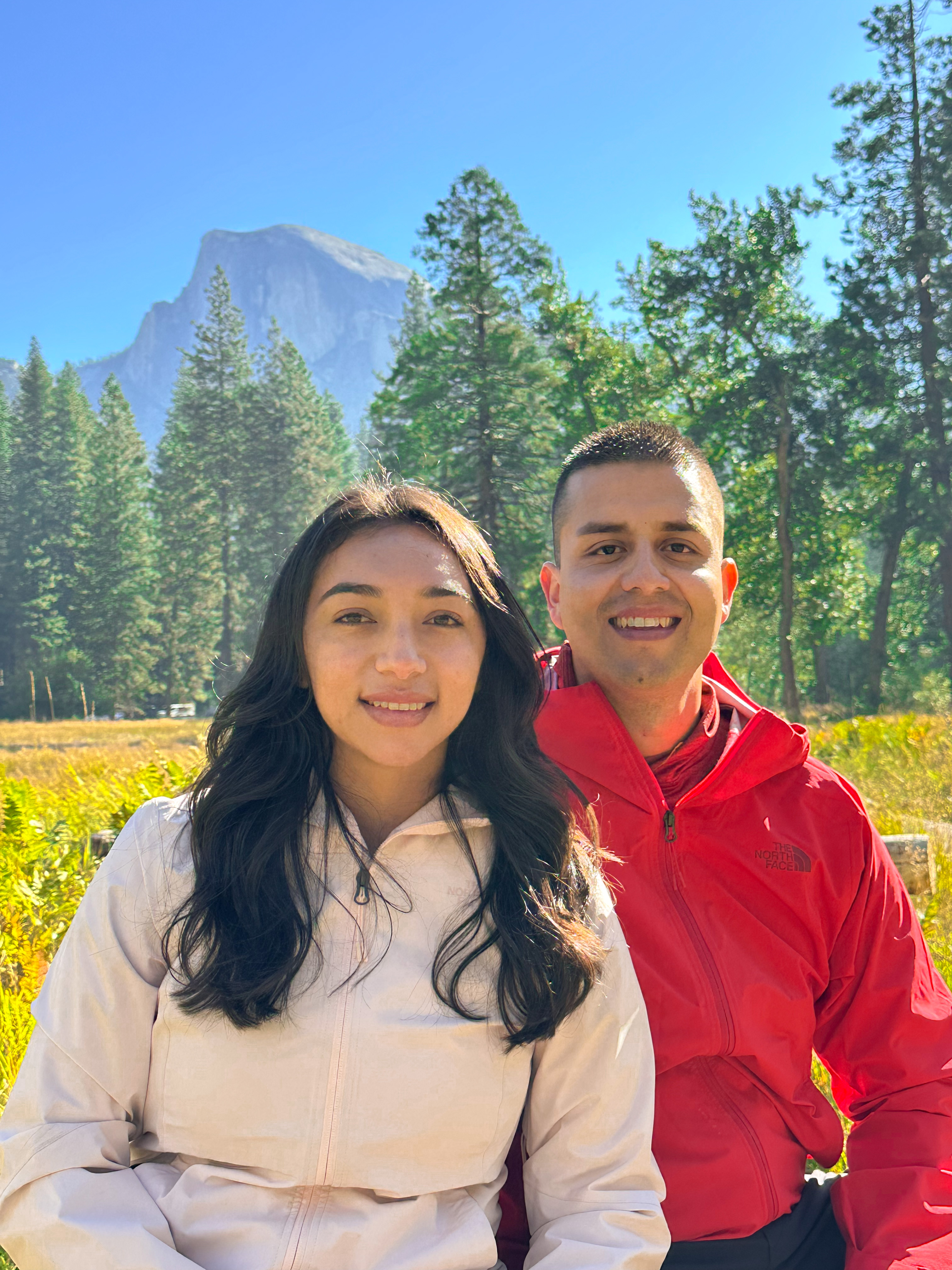 young man and young woman smiling happy in outdoors with mountain scenery in background featuring Yosemite National Park Half Dome 